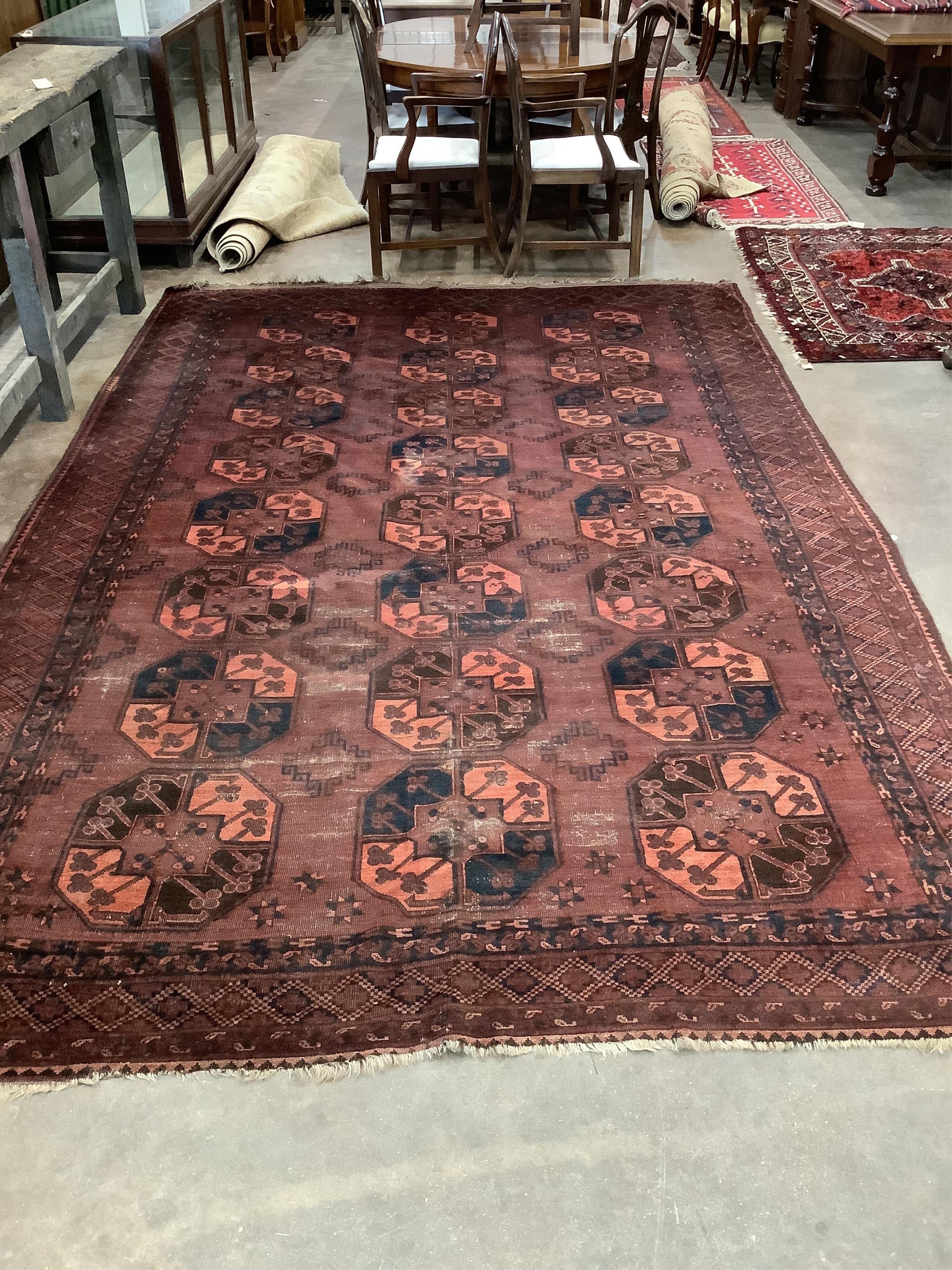 An Afghan red ground carpet, 380 x 240cm. Condition - poor to fair, one area of patching and several areas of low pile